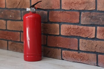 Fototapeta premium One red fire extinguisher on floor indoors, space for text