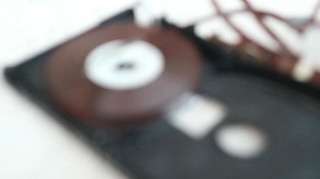 A close-up view of a vintage CD on a blurred black background with wires