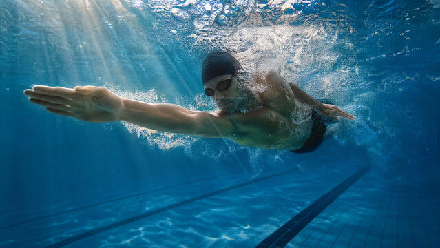 Man swimming underwater in blue pool