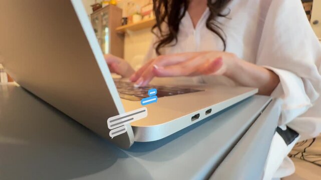 Angled close-up 4K footage of an Asian woman's hands typing text on a laptop keypad with perspective messaging balloons appearing.