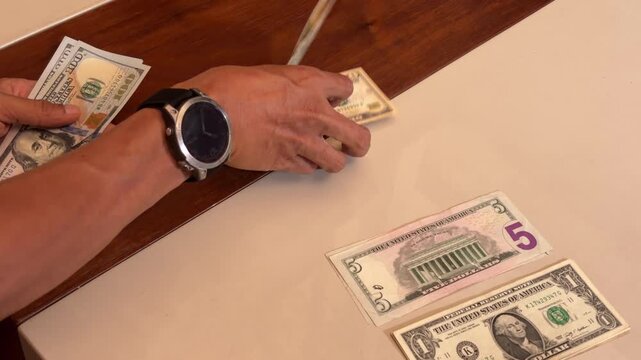 Asian male hand close up view of putting US dollar money bills on table