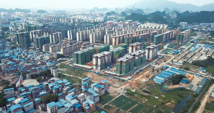 Aerial view of residential apartment construction and urban expansion beside karst mountains