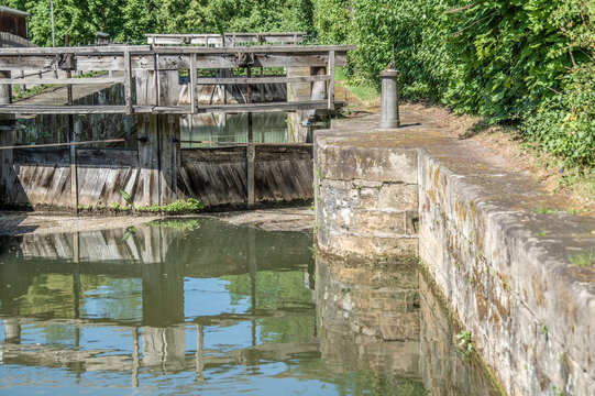 Historische Holzschleuse Schleuse 100 mit Eichenholztoren, gusseisernen Pollern und Einfassung aus Sandstein mit Spiegelung im Wasser des Ludwig-Donau-Main-Kanals am Flusspfad in Bamberg .