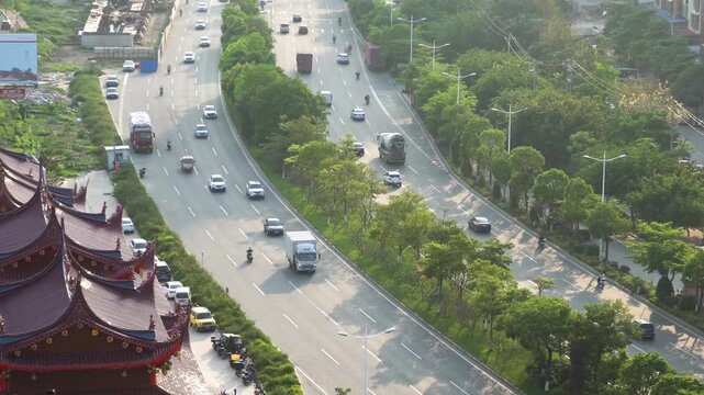 Aerial view of tree-lined urban boulevard with traffic and temple rooftops