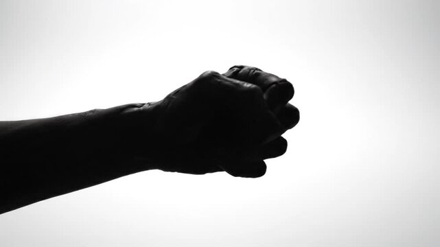 A dark silhouette of a hand with long sharp claws against a bright background