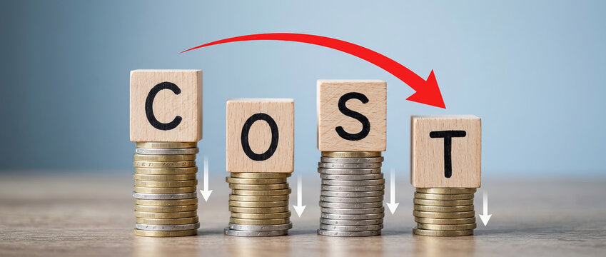 Cost reduction and expense management concept with wooden blocks spelling COST on coin stacks and descending arrows
