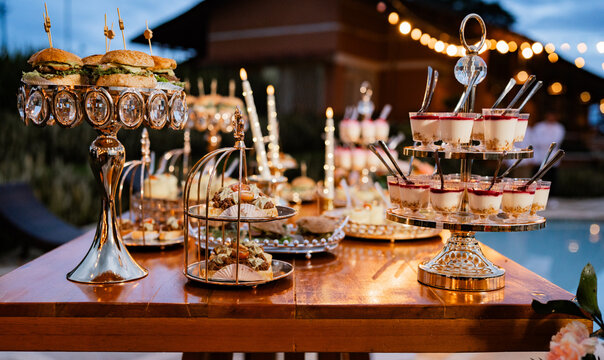 Mesa de catering elegante con aperitivos gourmet y postres en celebraci&oacute;n nocturna al aire libre