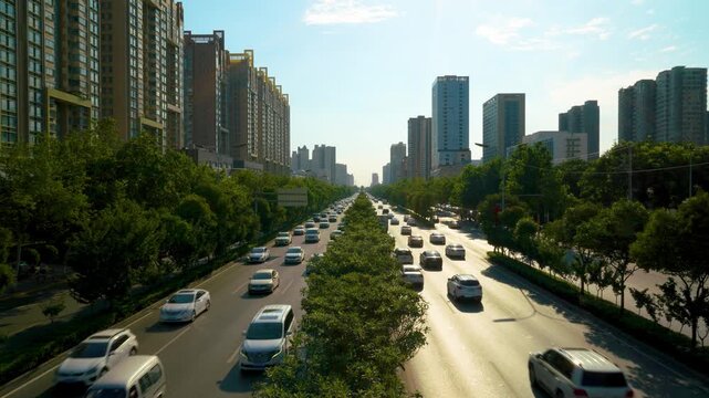 Busy urban boulevard traffic between high-rise residential buildings at sunset
