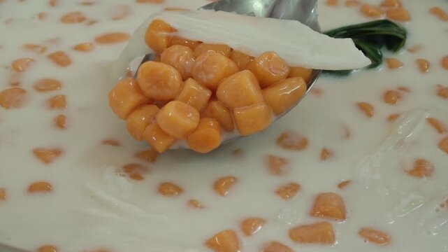 Colorful Bua Loy Thai dessert rice balls in coconut milk with poached egg