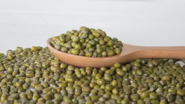 Wooden spoon filled with small green mung beans