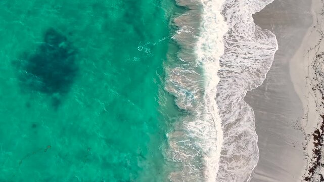 Aerial view of a tropical sandy beach on Saint Martin island in the Caribbean. Turquoise sea water with white foam waves rolling onto the shoreline. Tropical shoreline scenery on a sunny day.
