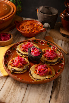Panuchos Mexican Food, a typical dish from Yucatan, Mexico. A handmade, fried corn tortilla filled with beans, topped with cochinita pibil, pickled red onion, and habanero pepper.