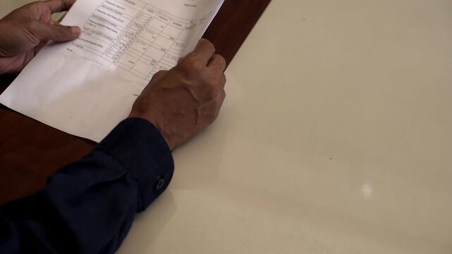 Asian male close up hand while checking paper detail document and making payment with US dollar money bills