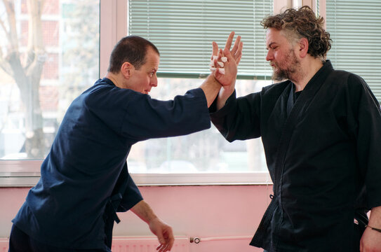 Two Men Practicing Martial Arts Self-Defense Techniques During Partner Training In A Dojo