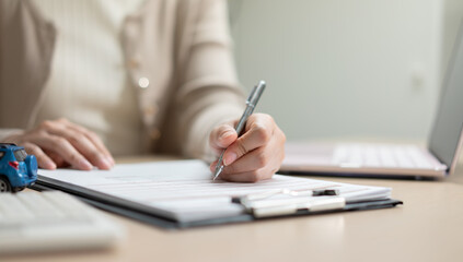 Fototapeta premium Businesswoman reviewing and signing insurance policies, loan agreements, and financial contracts for vehicle financing, risk protection, and business transactions.