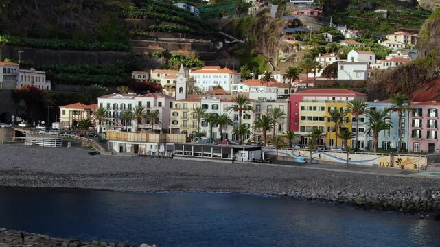 Picturesque aerial view revealing the charming village of Ponta do Sol on the coast of Madeira, showcasing its colorful houses and black pebble beach