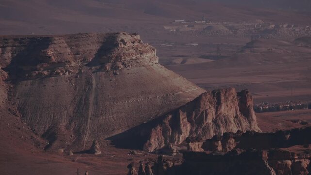 Cappadocia landscape shows rock formations and distant towns in daytime
