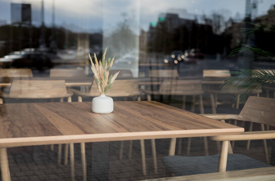 Empty cafe table with vase view through window glass.