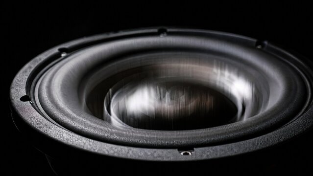 Close-up of subwoofer cone with motion blur under strobe light.