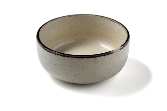 Beige ceramic bowl with chipped edge isolated on white background.