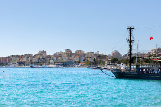 Black ship on the blue waters of Sarande marina in summer.