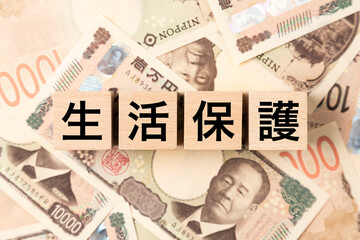 Fototapeta premium 「生活保護」と書かれたブロックとたくさんの一万円札