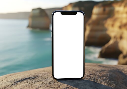 Smartphone with blank screen on rocky cliff by ocean