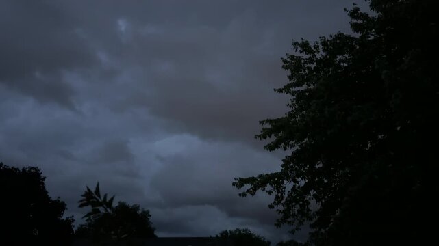 Fast moving dark storm clouds with lightning flashes at night