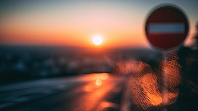 Blurred sunset over a road with a no-entry sign, casting orange light and bokeh