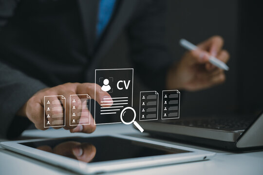 A businessperson reviews digital resumes using a laptop and tablet, highlighting modern recruitment and job application processes.