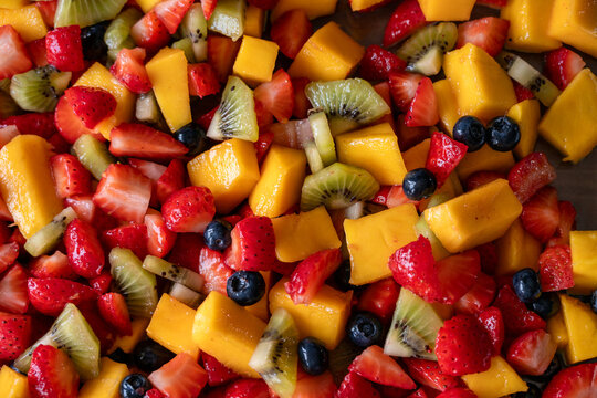 Vista superior de una macedonia de frutas cortadas con fresas, mango, kiwis y ar&aacute;ndanos