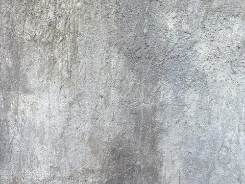 An old weathered concrete wall with a rough and porous texture. A large portion of the surface is covered in dark mold stains and patches of moss.