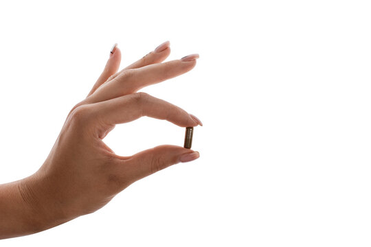 Hand holding brown capsule pill between fingers on white background, medication and healthcare concept