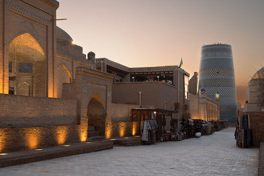 Kalta Minor minaret and illuminated brick walls of Ichan Kala old town at dusk in Khiva, Uzbekistan. Ideal for travel guides, tourism brochures, and cultural heritage publications.