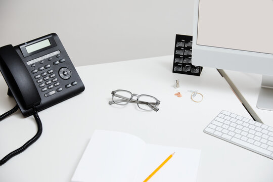 Modern office desk with telephone, notebook, and computer setup