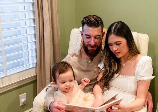 family sitting on chair, mom and dad reading to daughter Storytime 