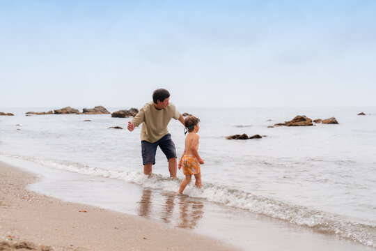Father throwing stones into water with son 