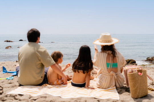 Family sitting on beach, watching ships and talking 
