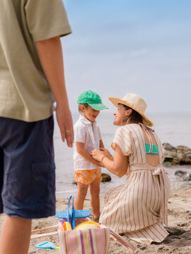 Mother is undressing little boy at beach 