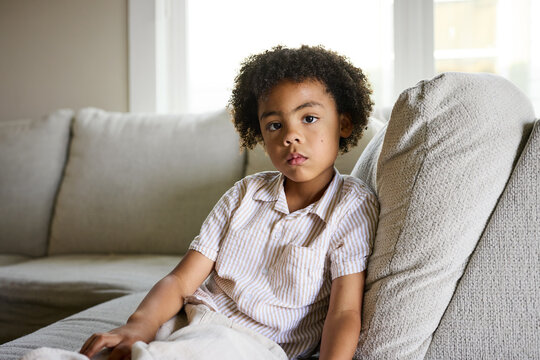 Child Sitting on a Sofa and Looking Straight Ahead