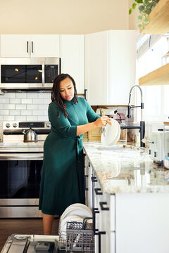 Woman Washes Dishes in a Modern Kitchen During Daytime