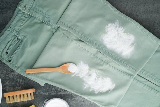 Green jeans sprinkled baking soda powder. Natural cleaning alternatives products for removing stains from clothes. Concept alternative and eco-friendly cleaning products. top view
