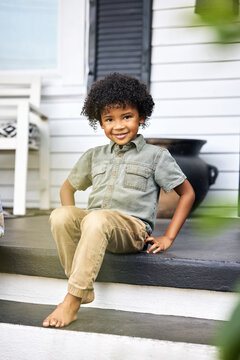 Young Boy Smiling on Porch Steps at Home