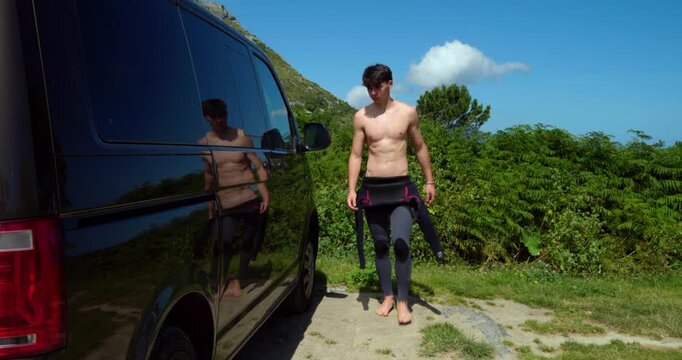 Surfer's Arrival: A young man, clad in a wetsuit and carrying surfing gear, emerges from a van ready to hit the waves, basking in the bright coastal sunshine.