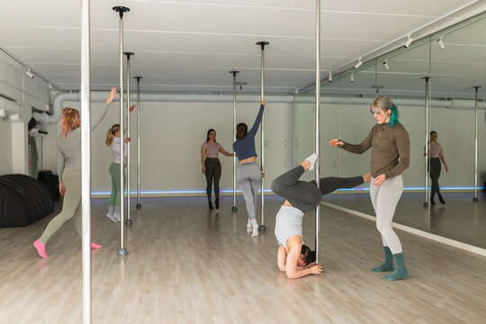 Female instructor coaching student in headstand pose