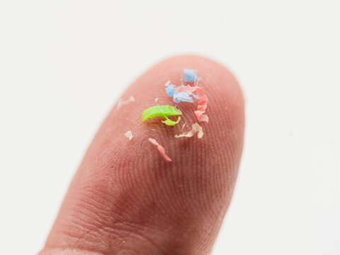 Trozos de micropl&aacute;sticos sobre un dedo de la mano