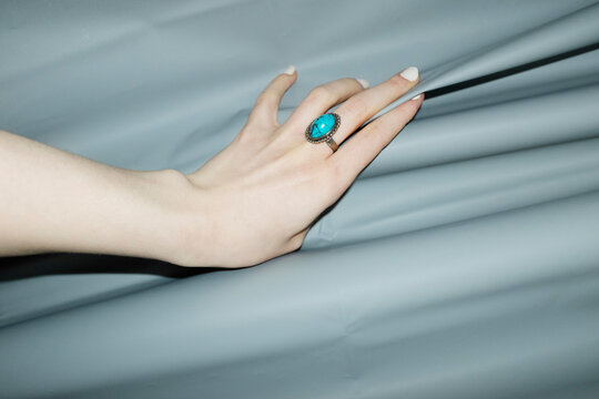 Hand with blue turquoise beautiful jewellery ring and opening curtain