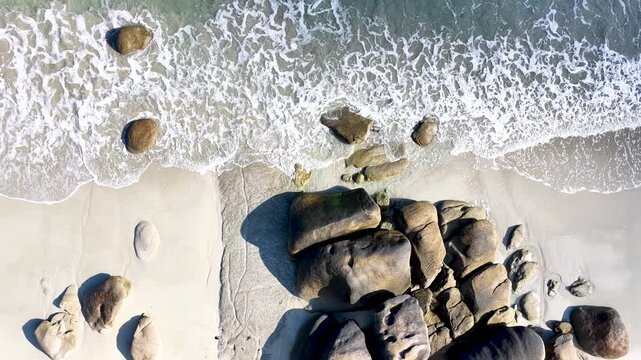 Spektakul&auml;re Drohnenaufnahme vom Plage de Boutrouilles: Wellen treffen auf feinen Sandstrand und imposante, runde Granitfelsen an der wilden K&uuml;ste der bretonischen Region.