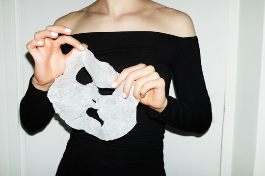 Person peeling of a beauty cosmetic facemask with hard flashlight