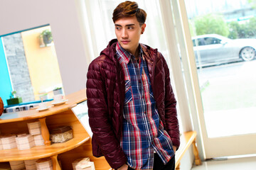 Fototapeta premium An Asian boy wearing a down jacket is inside a store.